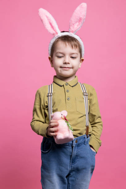 istock Young small child smiling in studio and holding a cute pink rabbit toy 2042721138