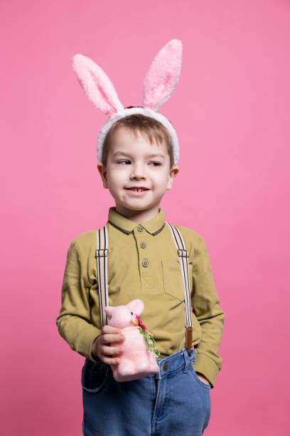 istock Adorable little kid smiling on camera and posing with a pink rabbit 2042721167