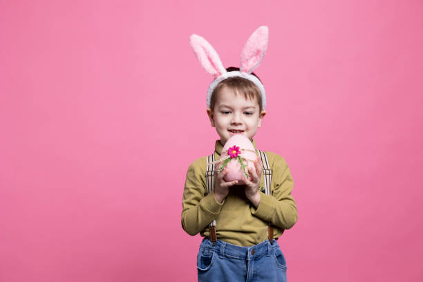 istock Little smiling kid presenting a pink painted egg in front of camera 2042721200