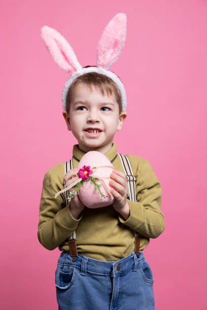 istock Joyful young child showing a pink egg decorated for easter 2042721226