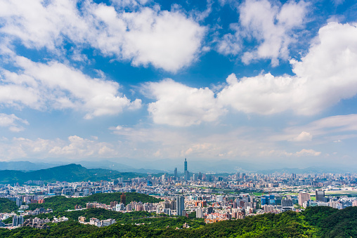 Overlooking view of the modern urban landscape of the Taipei area in Taiwan. It's a basin terrain surrounded by mountains.