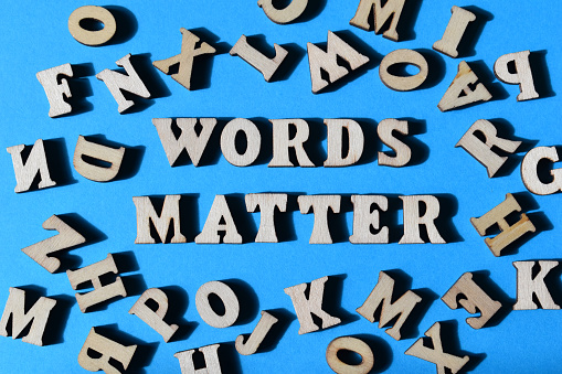 Words Matter, phrase in wooden alphabet letters surrounded by random letters on blue background