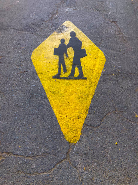 Black and yellow painted sign of School. Attention school sign painted on concrete road. car drivers take care of pupils in traffic.