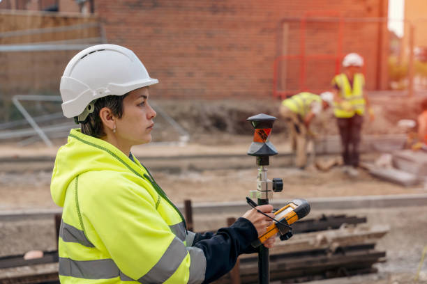 close-up portrait of a woman site engineer surveyor working with theodolite total station edm equipment on a building construction site outdoors - people in a row in a row business office worker zdjęcia i obrazy z banku zdjęć