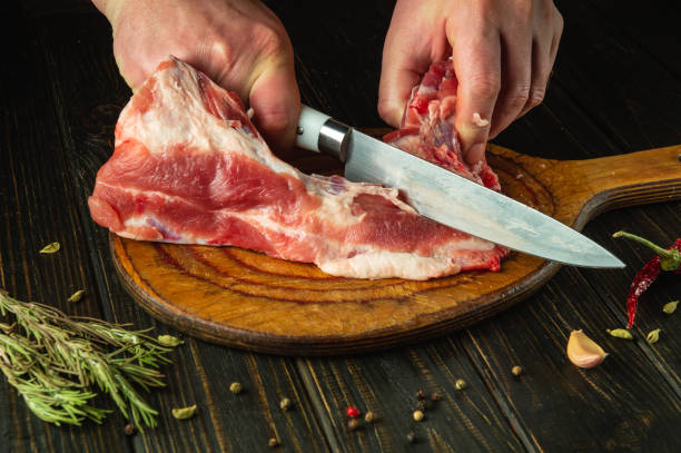 istock A cook cuts raw meat with a knife on a cutting board before preparing a meat dish. Recipe idea for a hotel or restaurant 2042765900