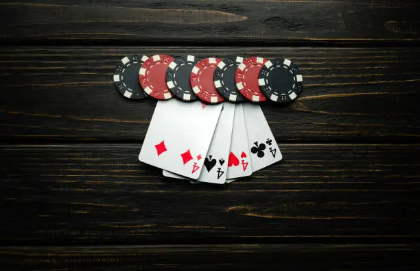 Photo of The popular poker game with a winning combination of four of a kind or quads is also interesting. Chips and cards on a dark vintage table in a poker club