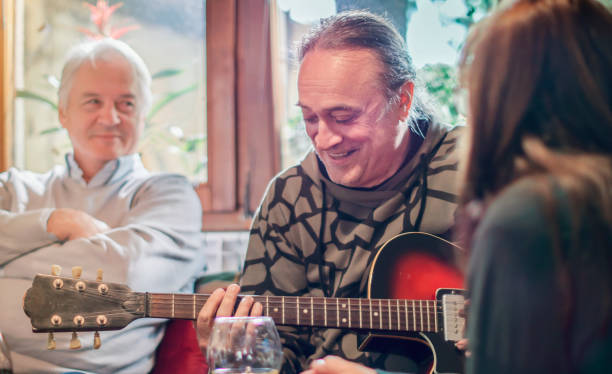 Senior playing the guitar surrounded by his friends