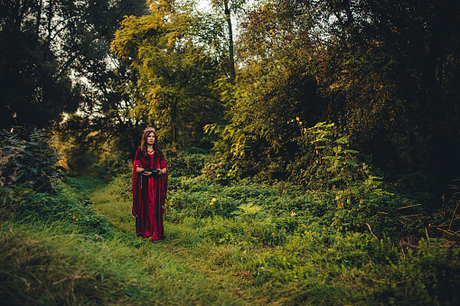 Young woman dressed like an evil queen standing in the forest.