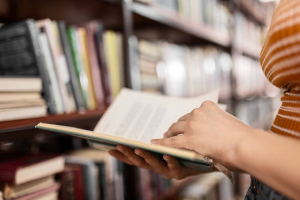 istock Unrecognizable female student next to bookshelves reading book 2042815546