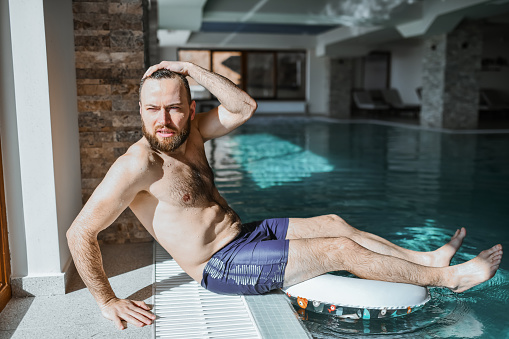 Male Looking Out Of Resort Window While Relaxing In Swimming Pool