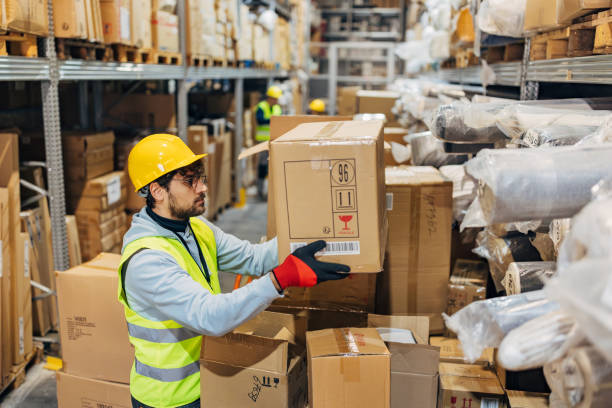 istock Male warehouse worker arranges cardboard houses in warehouse 2042834474