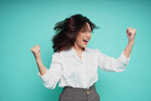istock A young Asian woman with a happy successful expression wearing white shirt isolated by blue background 2042838245