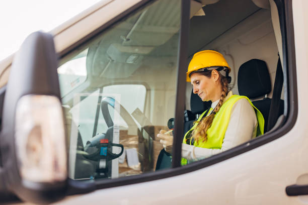istock A female worker in a reflective uniform sits in a delivery van and records information about delivered packages 2042850966