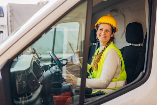 istock Cheerful female warehouse worker sitting in a delivery van and looking directly at the camera 2042850975