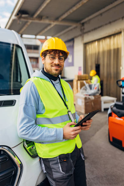 istock A handsome worker stands leaning against a delivery van and looks directly into the camera 2042851512