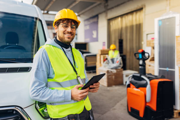 istock A handsome worker in a wholesale warehouse is leaning against a delivery van and looking directly into the camera 2042851518