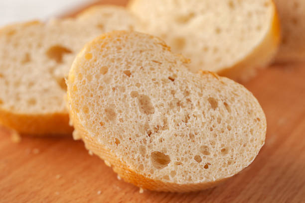 Fresh baked French baguette cut into slices on a cutting board