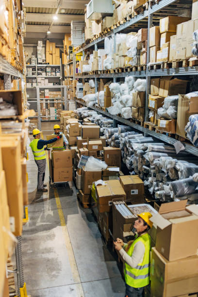 istock A warehouse worker reads the shipment list on a digital tablet while her colleagues remove cardboard boxes from the shelves and stack them on hand truck 2042859570