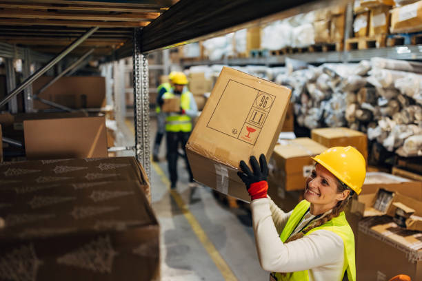 istock A smiling female worker removes a cardboard box from a shelf in a warehouse 2042870972