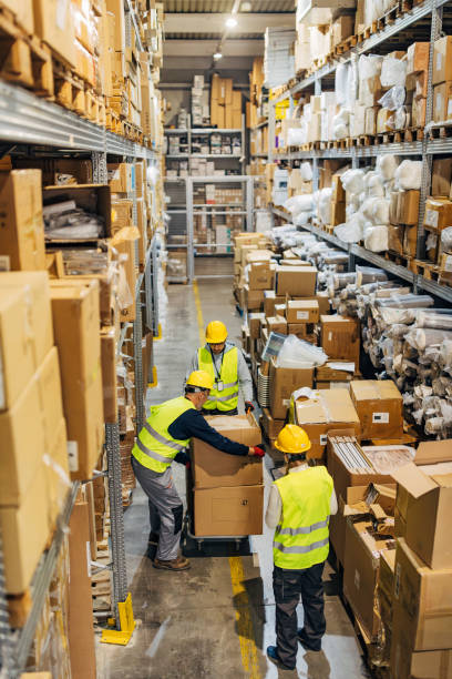 istock Warehouse full of cardboard boxes and three workers working as a team in the warehouse 2042874153