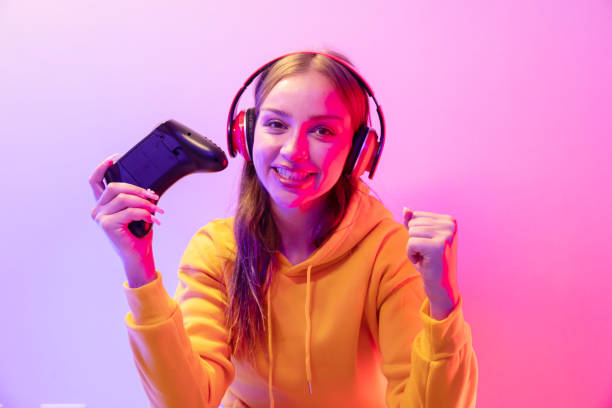 istock Woman Holding Game Controller Playing video game on neon light background 2042875272