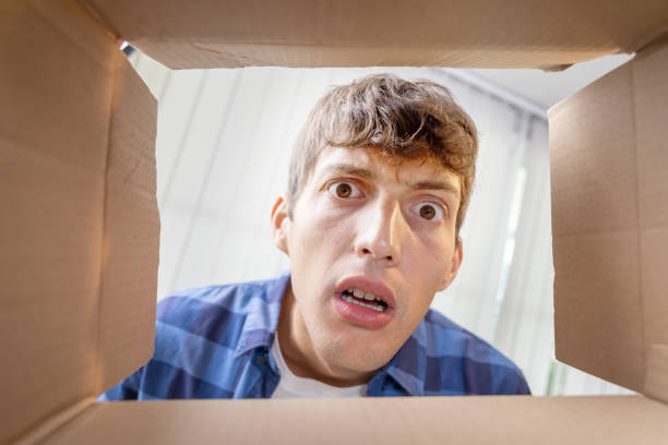 Caucasian Man Opening a Cardboard of Postal Package Box with Curiosity Face