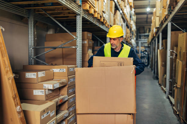istock A warehouse worker pushes a hand truck onto which he places cardboard boxes 2042876154