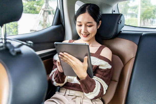 istock Young Asian woman using a tablet while sitting in a car. 2042891389
