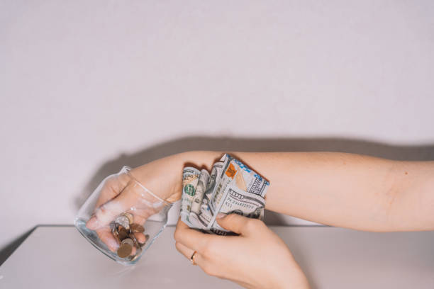 istock Hands take out dollar bills and coins from a glass jar 2042899479