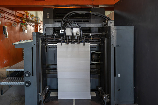 Printed sheets of paper are served in the printing press. Offset , CMYK. Offset printing machines. Large printing machine perspective.