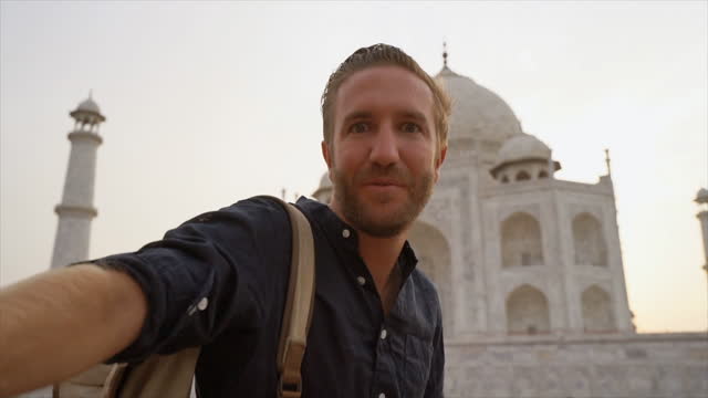 Male tourist taking selfie at the famous Taj Mahal using mobile phone, Agra, India. People travel Asia