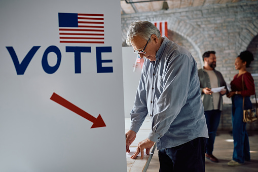 Senior citizen voting at polling station during elections in USA.