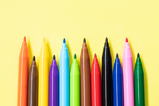 Colored markers isolated on yellow background