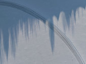 Abstract photo texture background. Winter scene, shadow from trees on a snow-covered field through which a road for transport passes.