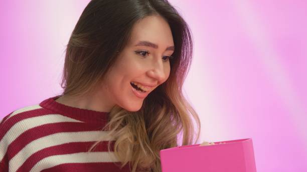istock Young woman opens a gift box and is pleasantly surprised 2042949106
