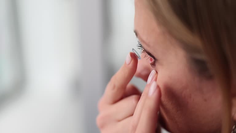 Woman puts contact lenses on eyes with finger