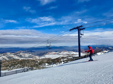Brian Head, Utah, USA- February 19, 2024: Lone skier under a lift, Brian Head ski resort, Utah.