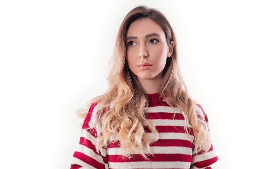 Serious young girl in a striped sweater on a white background