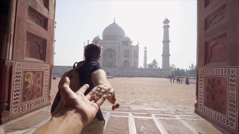 Follow me to the Taj Mahal, India. Male tourist leading girlfriend to there magnificent famous Mausoleum in Agra. People travel concept