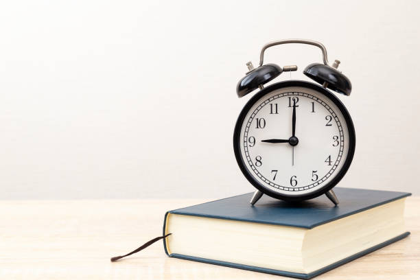 istock A thick book and a clock on the desk. 2043003207