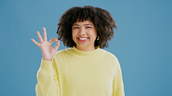 Happy, portrait and woman sign ok with hand in studio on blue background with feedback or opinion. Positive, review and emoji of girl with gesture for okay, thanks and agreement with fashion mockup