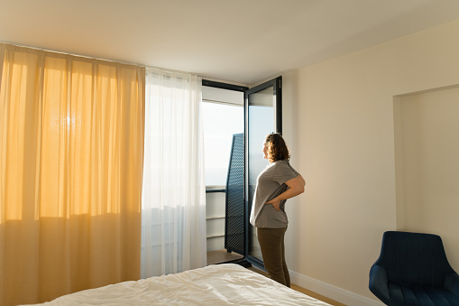 Woman with backache looking through window in the morning