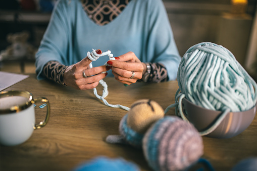 young woman working from home -knitting toys
