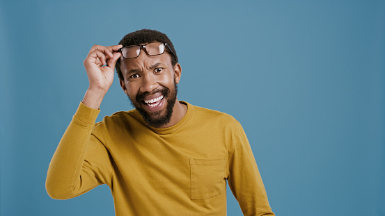 News, surprise and portrait of black man in studio, blue background and announcement mock up. African, person and shocked model with glasses and wtf, crazy reaction to secret, gossip or information