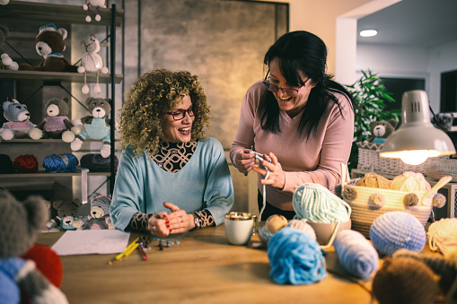 senior woman helps her daughter with knitting