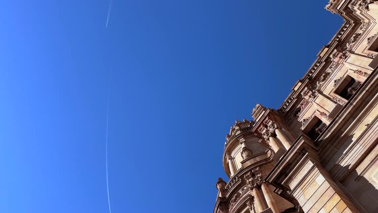 Historic old building exterior and flying commercial airplane over sky