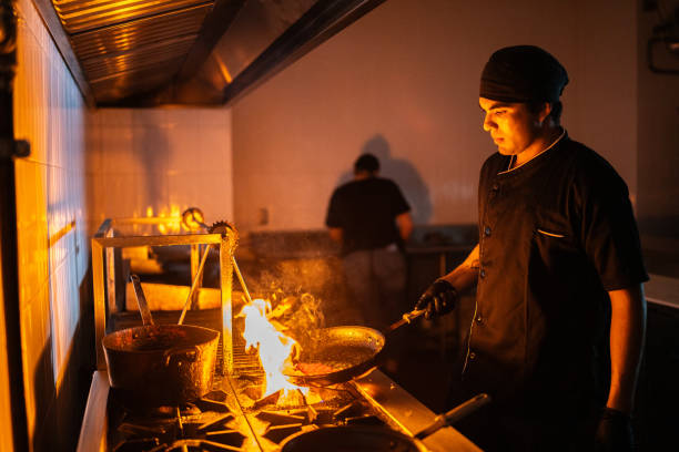 Young chef man flambe a food at restaurant kitchen