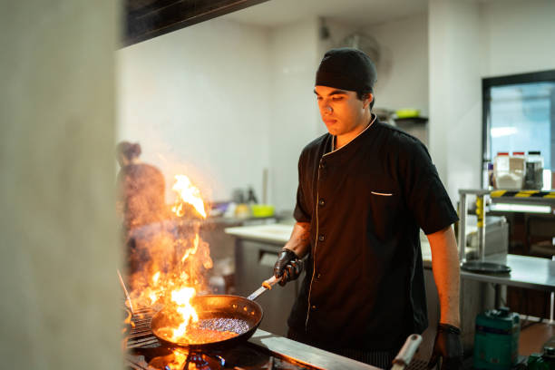 Young chef man flambe a food at restaurant kitchen