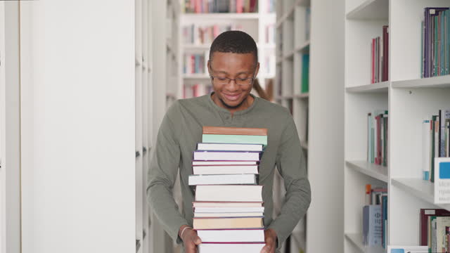Black man with book stack in library