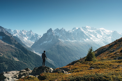 Backpacker with backpack enjoying the turquoise Lago di Sorapiss 1,925m altitude (mountain lake) view as he has mountain walk in Dolomite Mountains, Italy. Active people in nature concept.